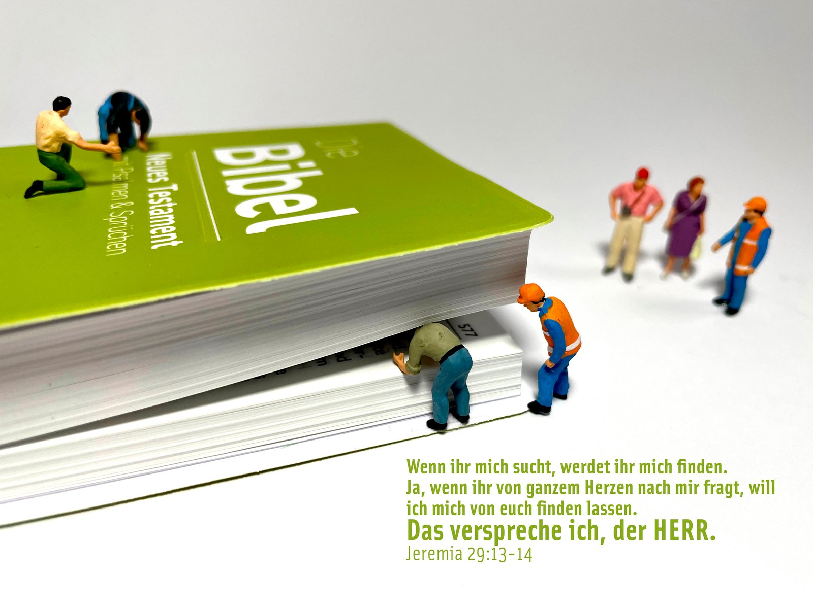 Miniatur-Arbeiter suchen in den Seiten einer Bibel, dazu Jeremia 29,13–14: „Wenn ihr mich sucht, werdet ihr mich finden.“