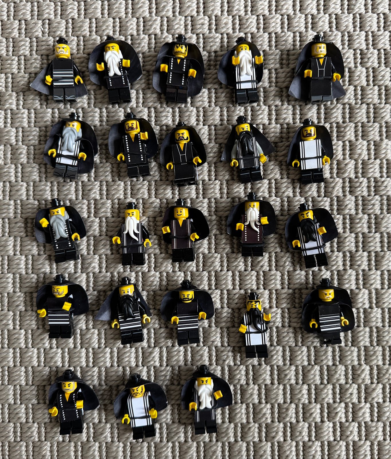 Über zwanzig Pharisäer-Minifiguren mit Bärten, Hüten und schwarzen Papierumhängen in Reihen auf einem Teppich