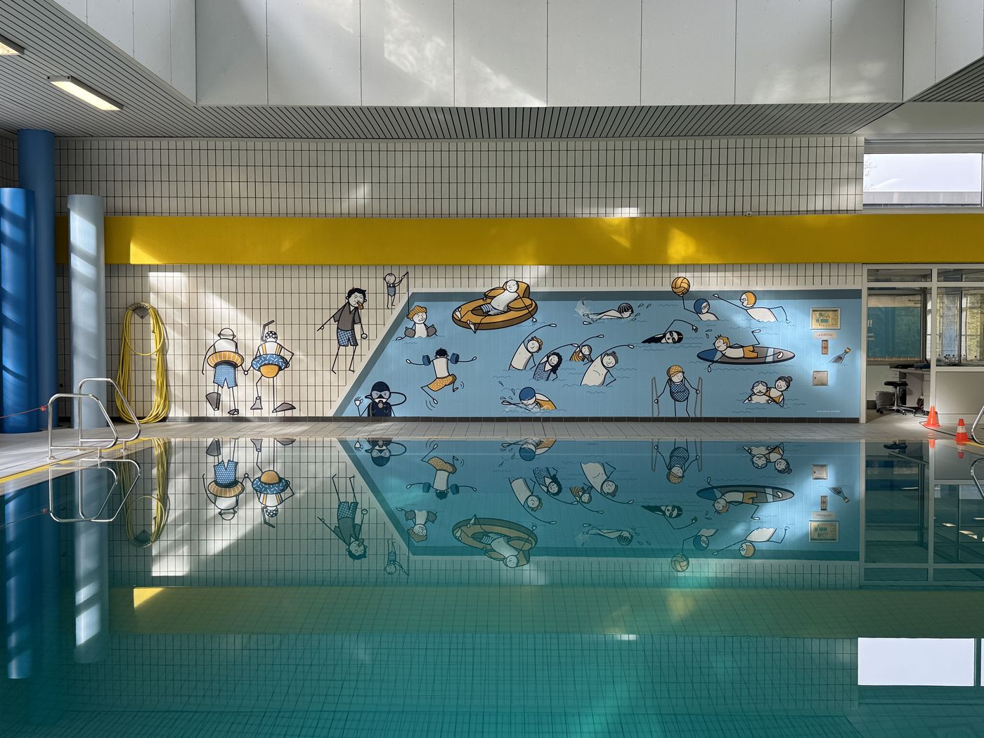 Gesamtansicht der Wandgestaltung im Hallenbad mit Spiegelung im Wasser